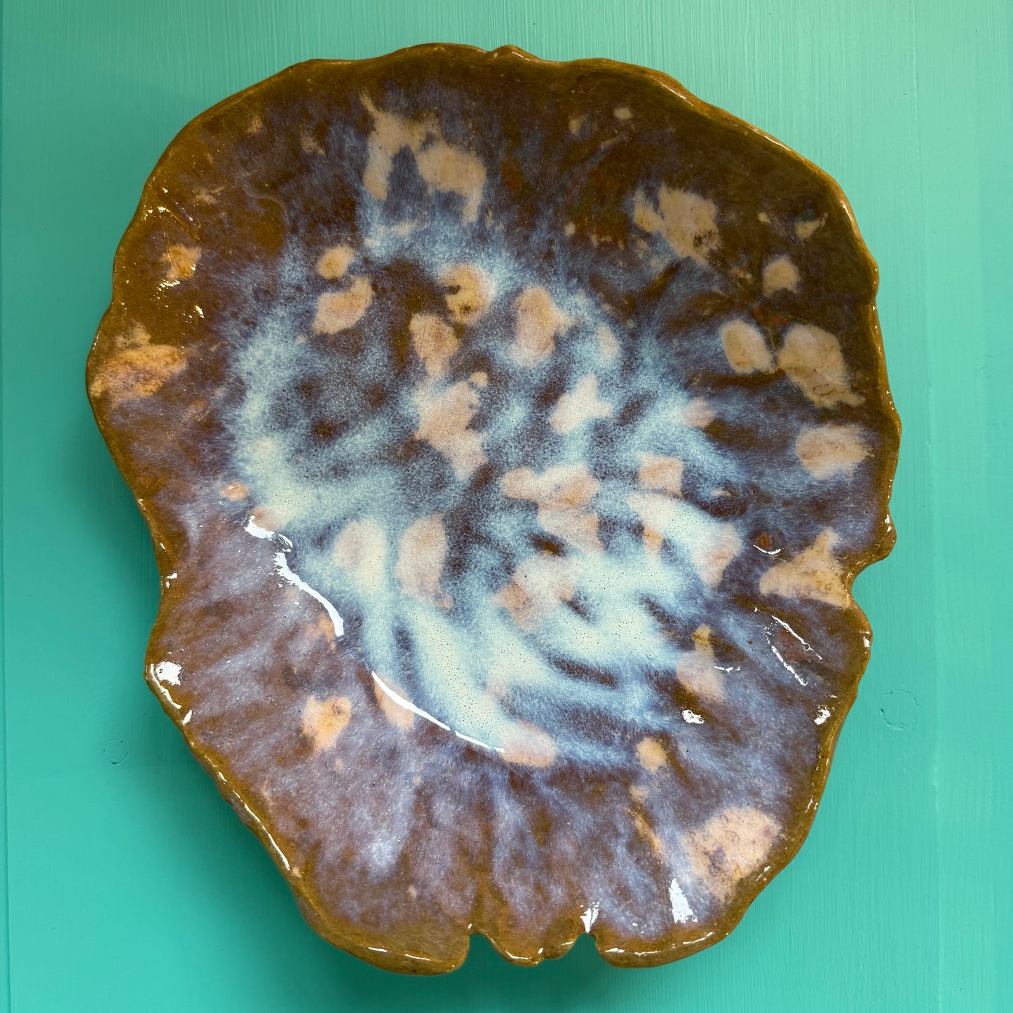 Ceramic plate with a unique glaze pattern on a teal background