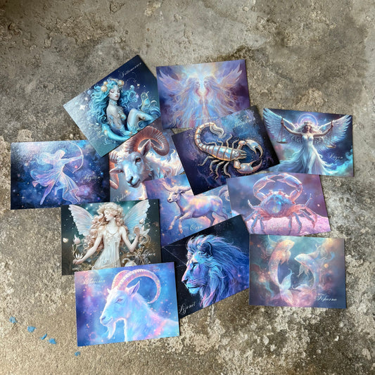 Collection of zodiac-themed postcards on a textured surface