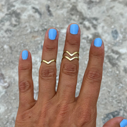 Hand with blue nail polish wearing three upperfingerrings in brass  