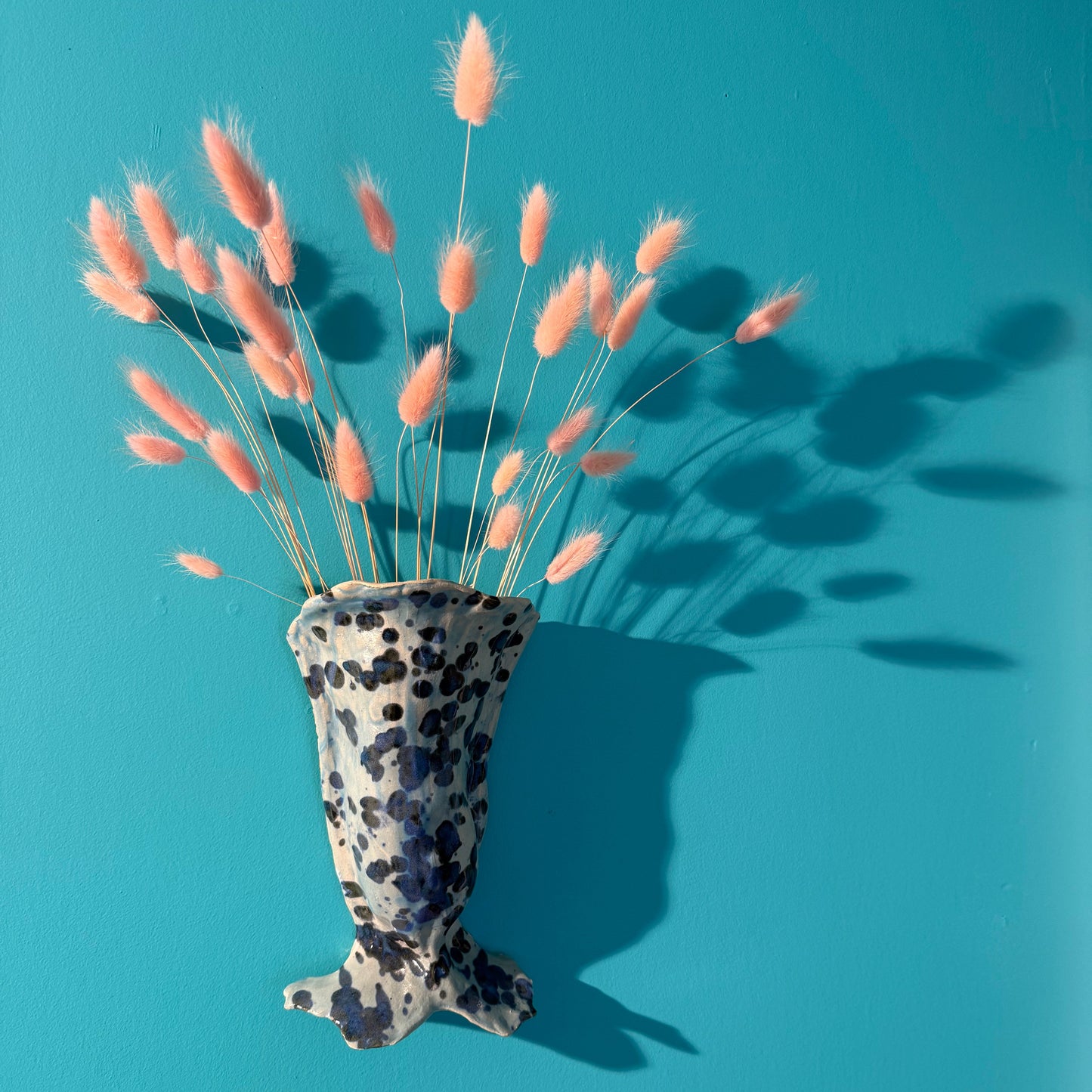 ceramic mermaid vase on a turquoise wall