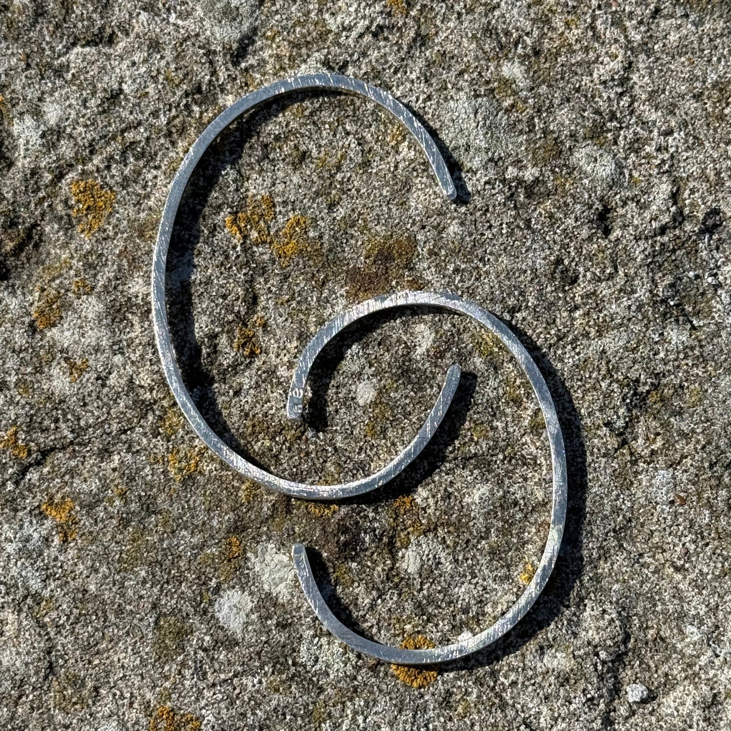 CC silvr cuffs on a textured stone surface