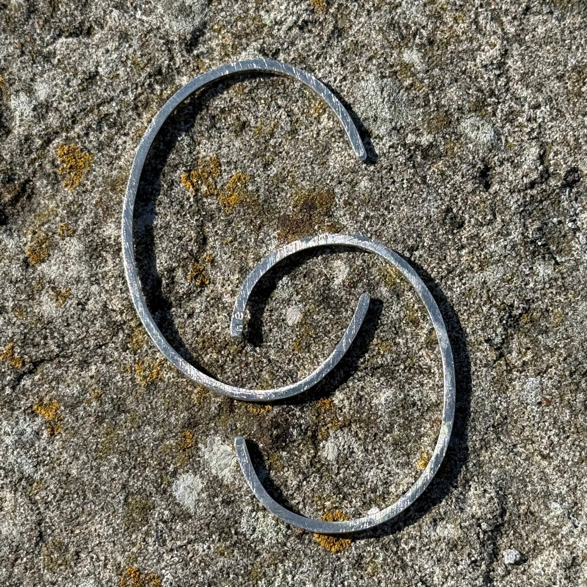 CC silvr cuffs on a textured stone surface