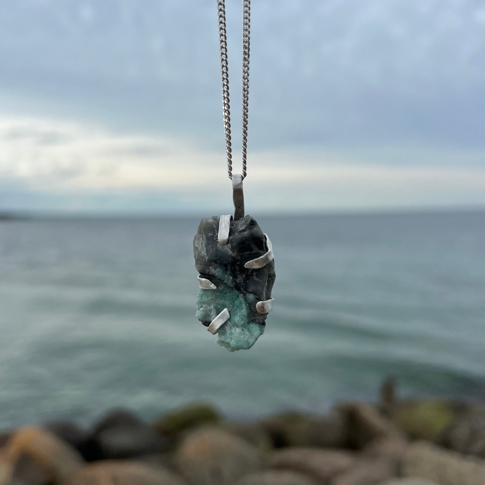 Necklace with emerald silver pendant against a blurred natural background