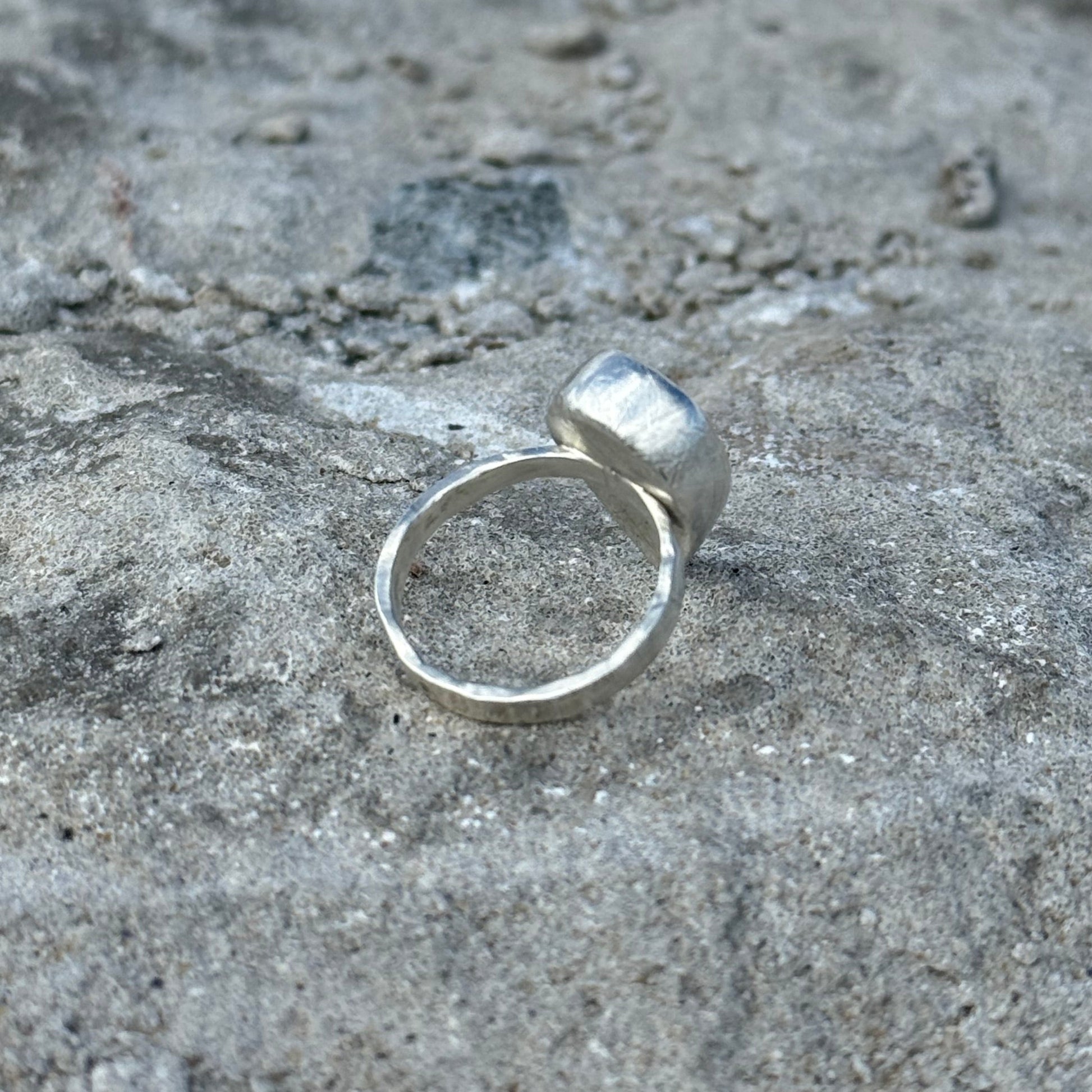 hammered and brushed Silver ring on a textured gray surface