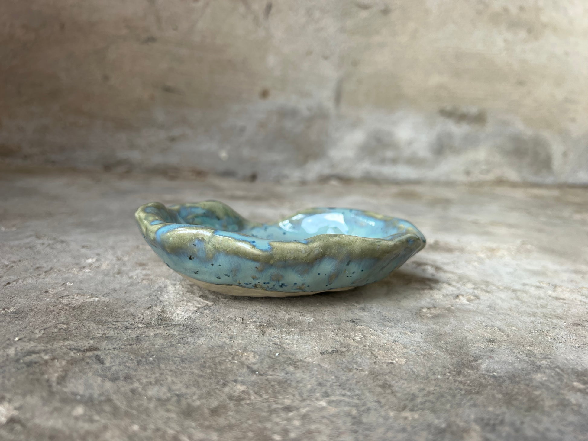 Small ceramic soap dish with a textured surface on a stone surface