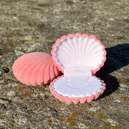 Pink shell-shaped for earrings, necklace and ring, on a textured stone surface