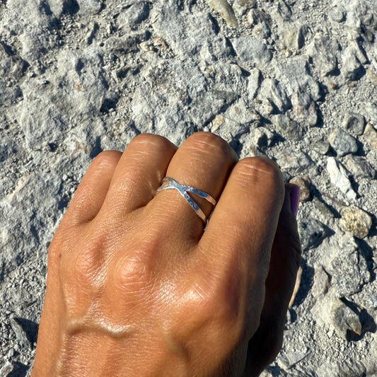 Hand with a silver infinity ring on a textured stone surface
