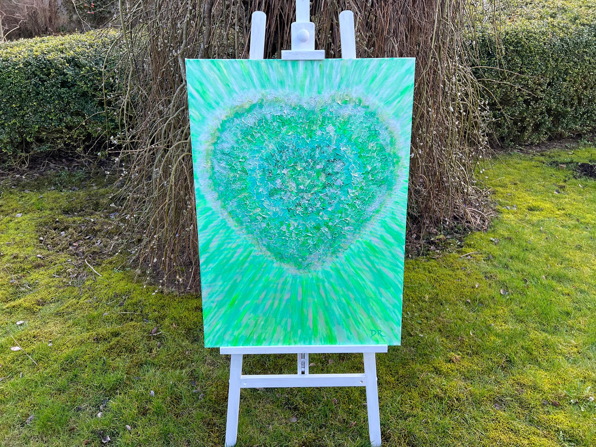 Painting of a green heart on an easel outdoors