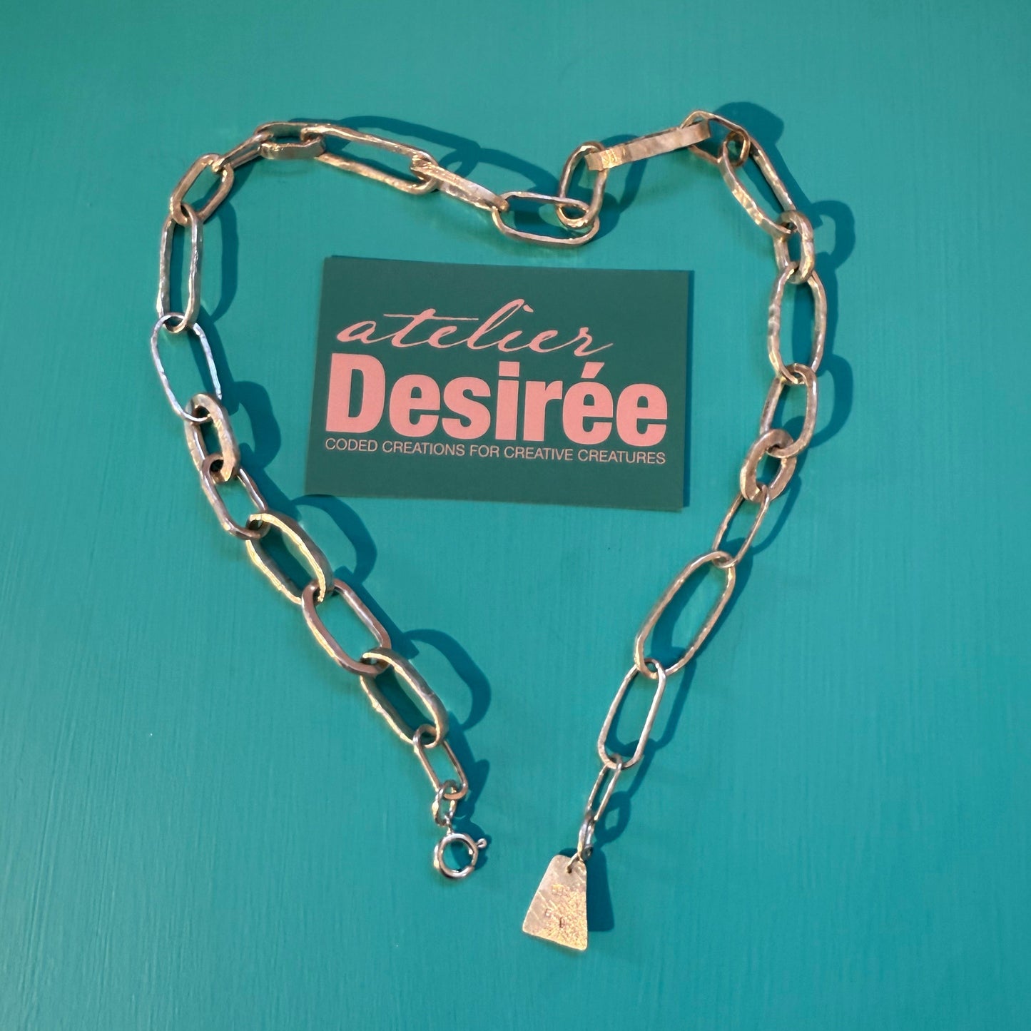 Silver chain necklace on a teal background with a Desiree card.
