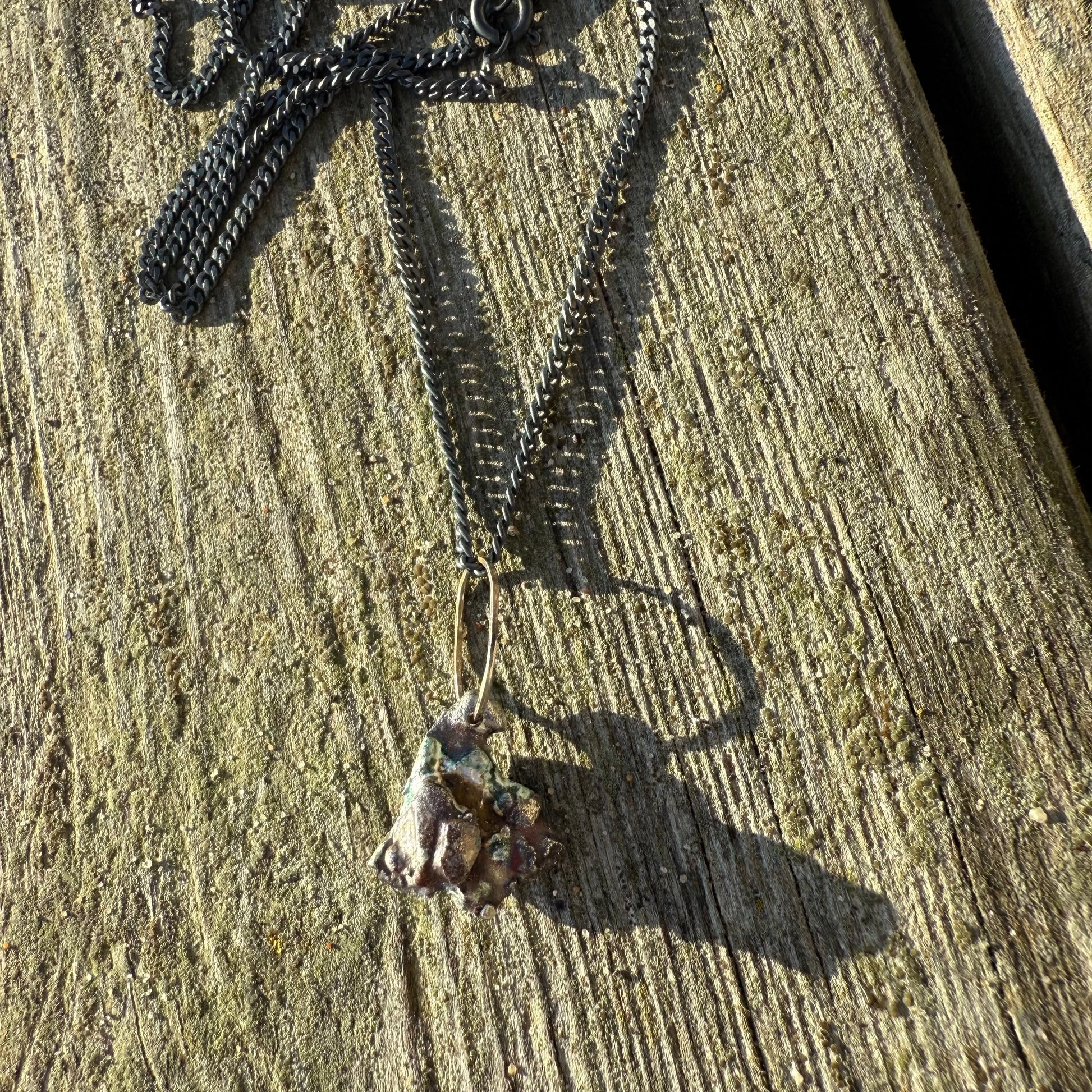 Oxidizeed silver Necklace with a stardust pendant on a wooden surface